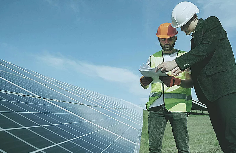 engineer and staff standing near solar panels